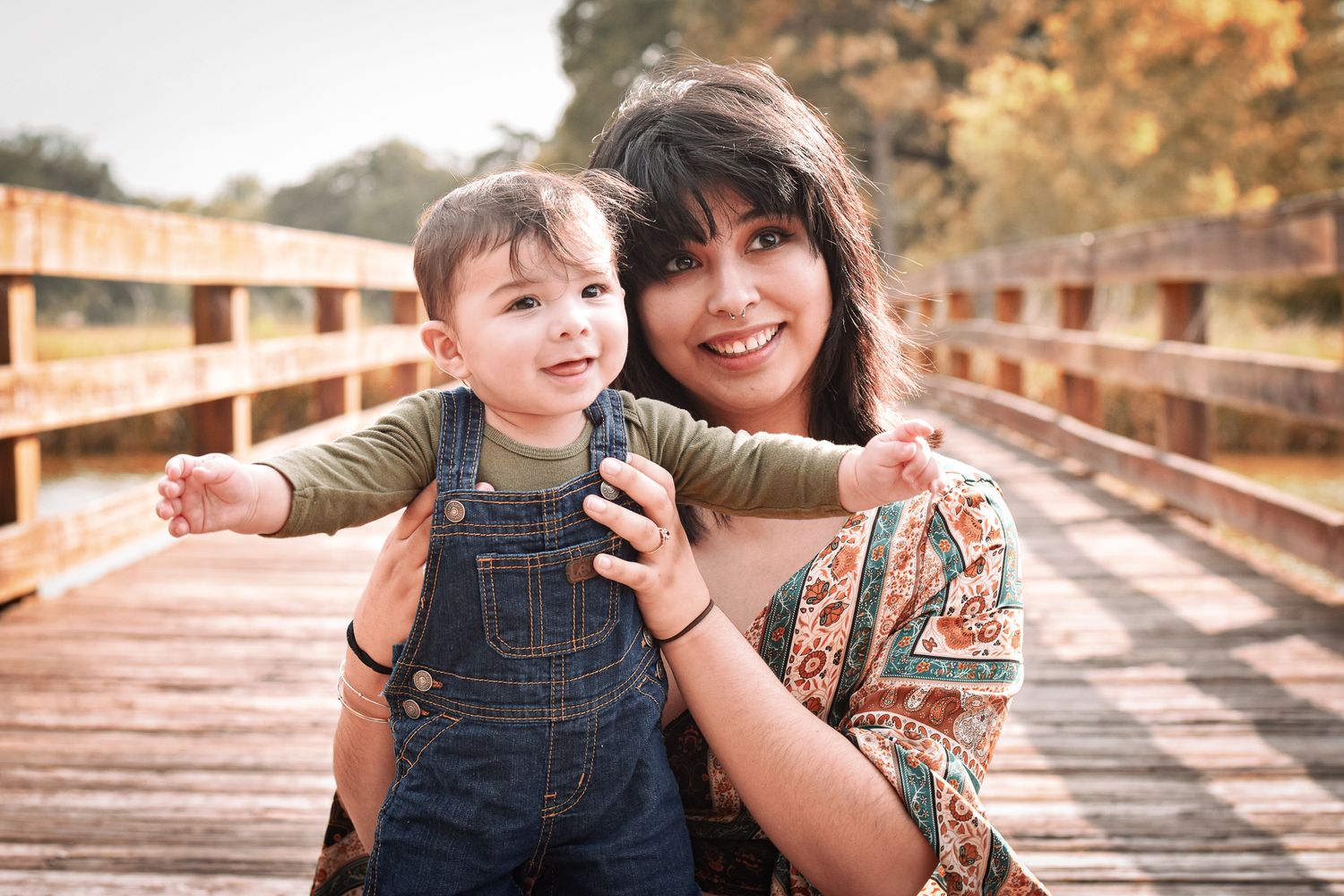 Sweet candid moment between parent and child on wooden bridge outdoors.