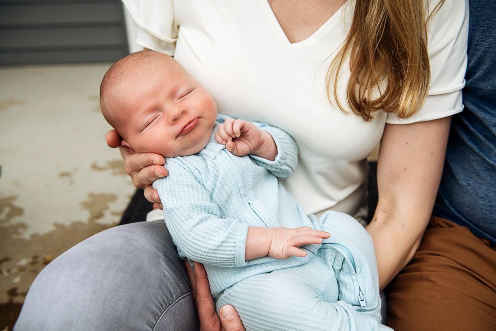 Baby in light blue outfit resting peacefully on white fabric.