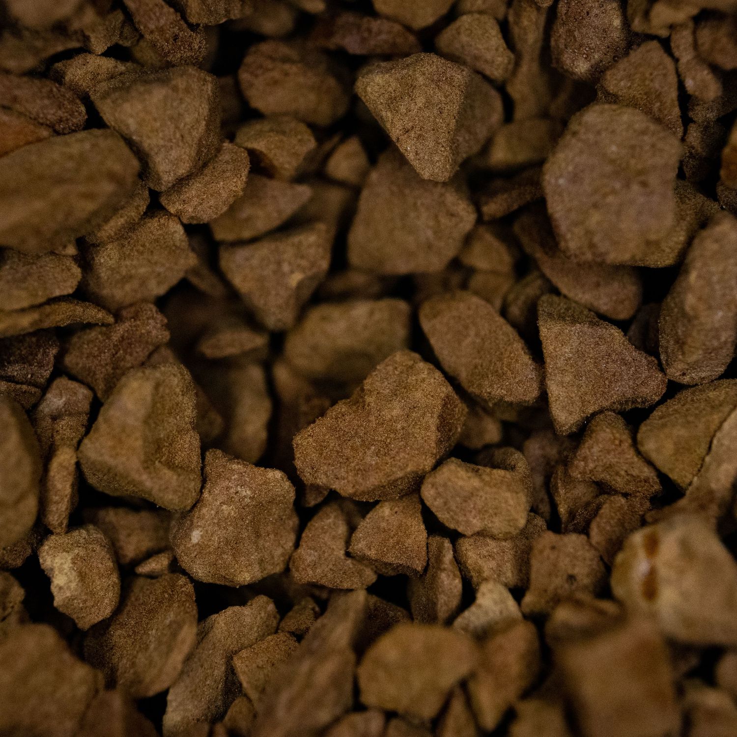 Close-up macro shot of brown coffee grounds or cocoa nibs texture.