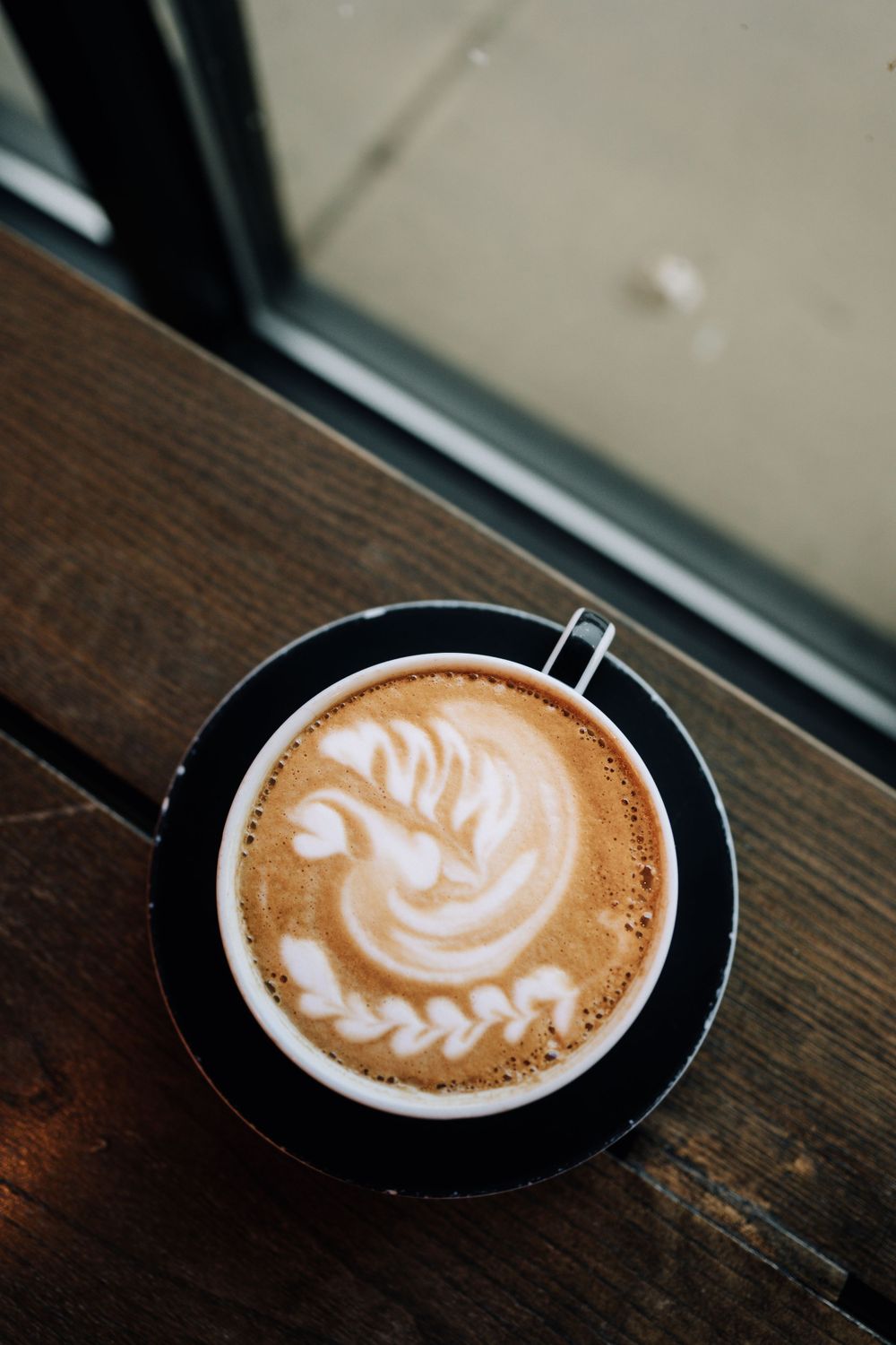 Overhead view of latte art showing intricate leaf pattern in coffee foam.