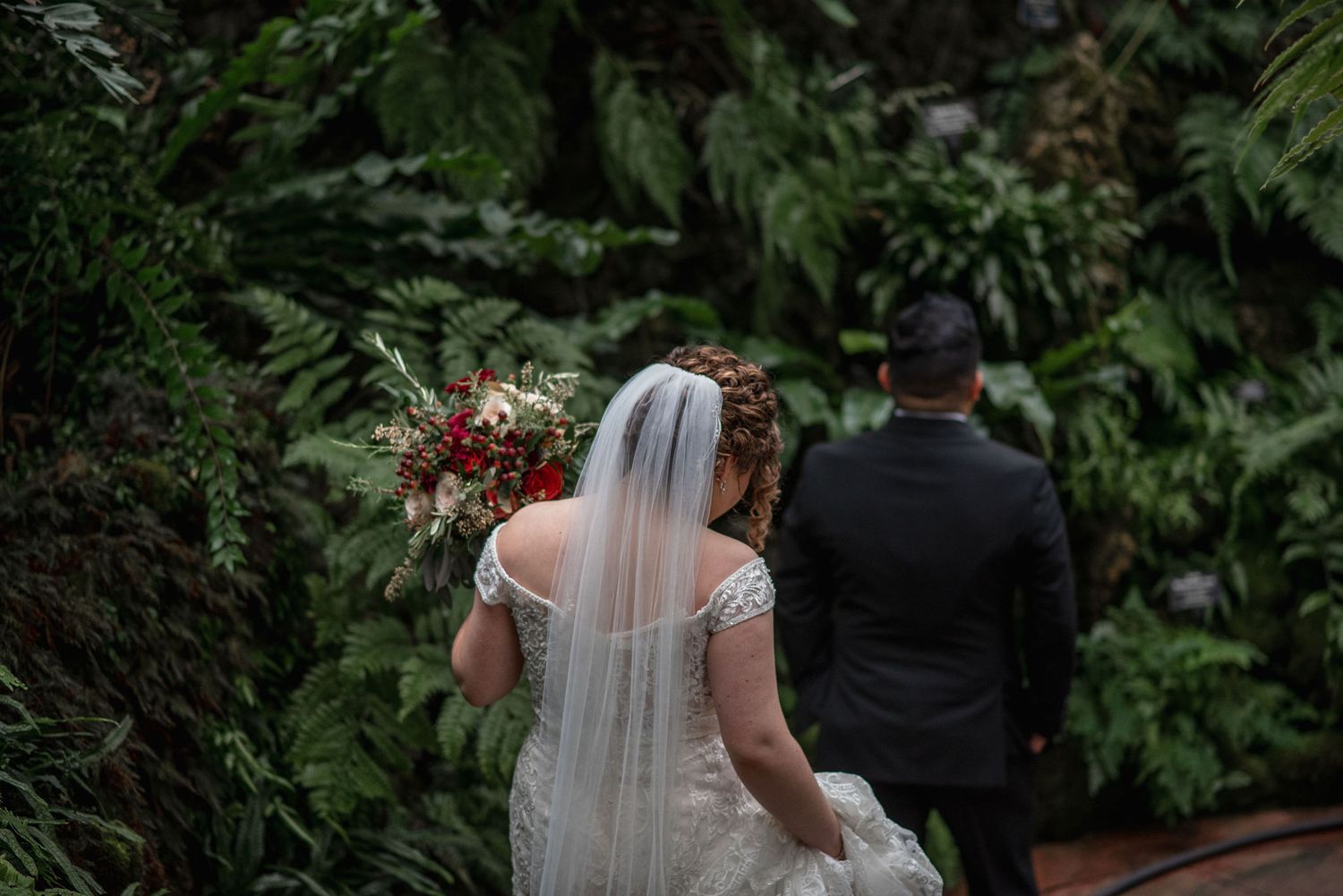 A couple shares an intimate moment surrounded by tropical greenery and ferns.