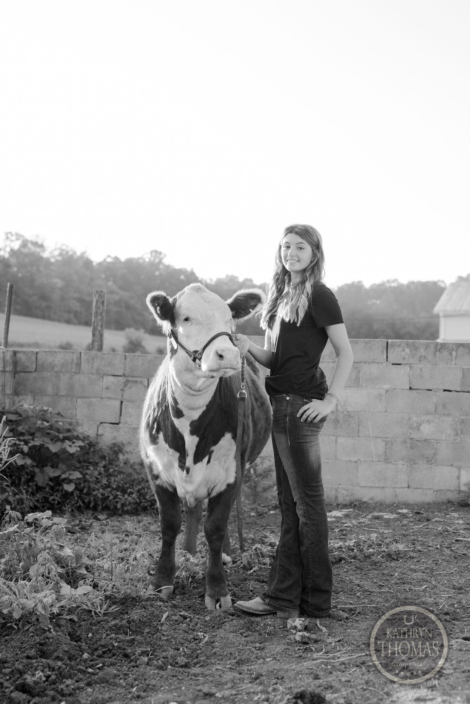 A black and white dairy cow poses with its handler in a rustic farm setting.