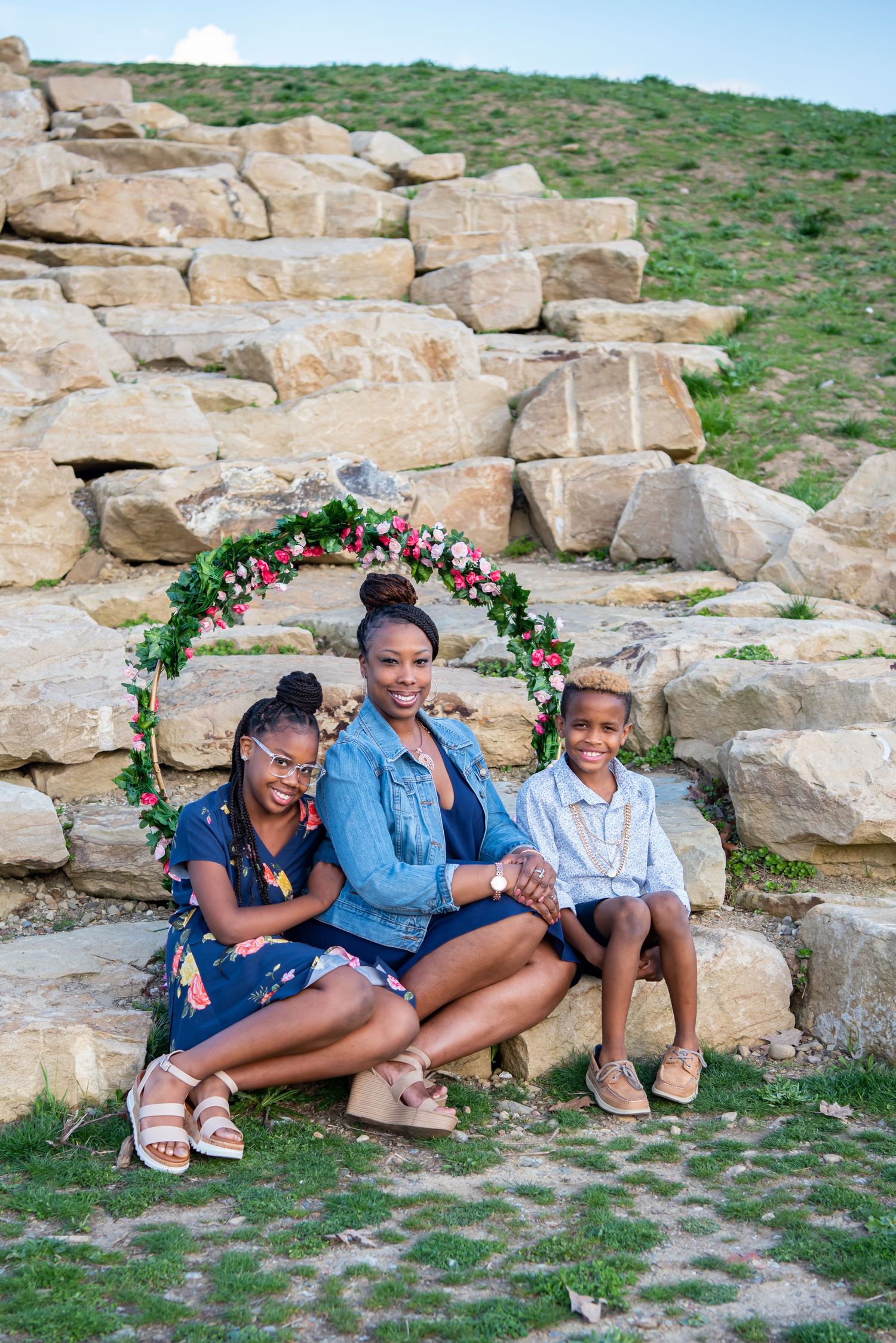 mom and two kids sitting on rocks with floral hoop in north park