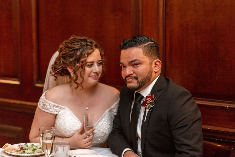 Couple shares intimate moment at wedding reception table with romantic lighting.
