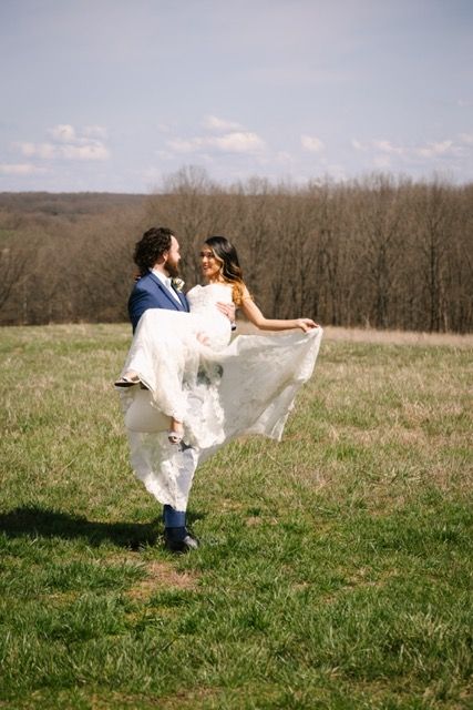 Groom holding his bride as they spin around in a big open field