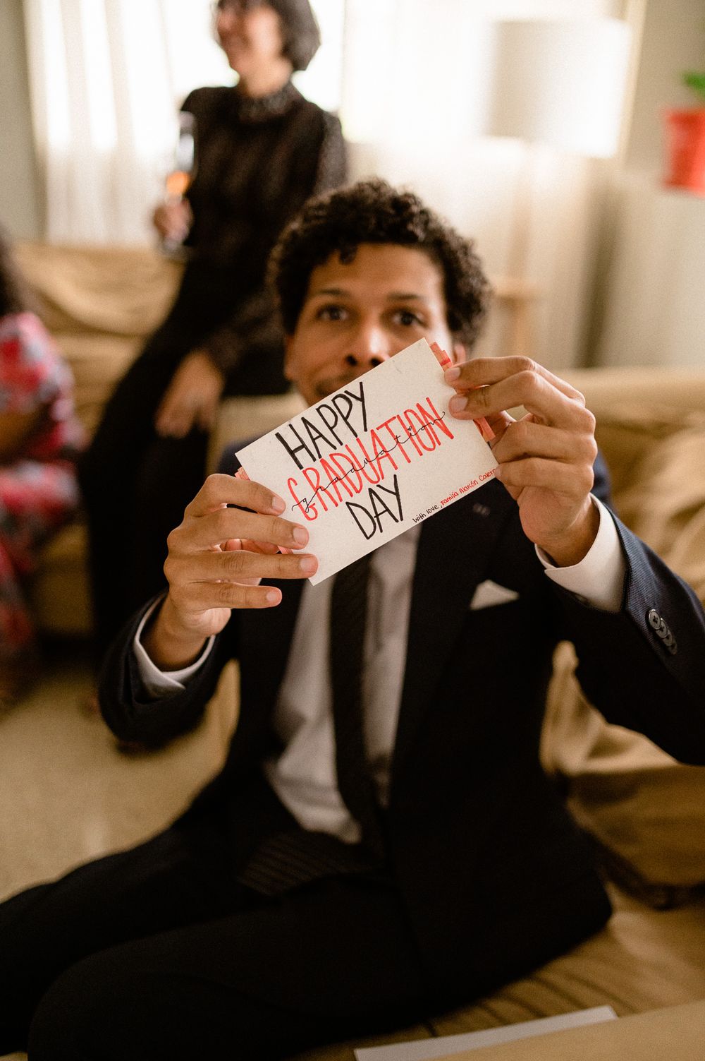 Person in suit holding up Valentine's Day card with handwritten text.