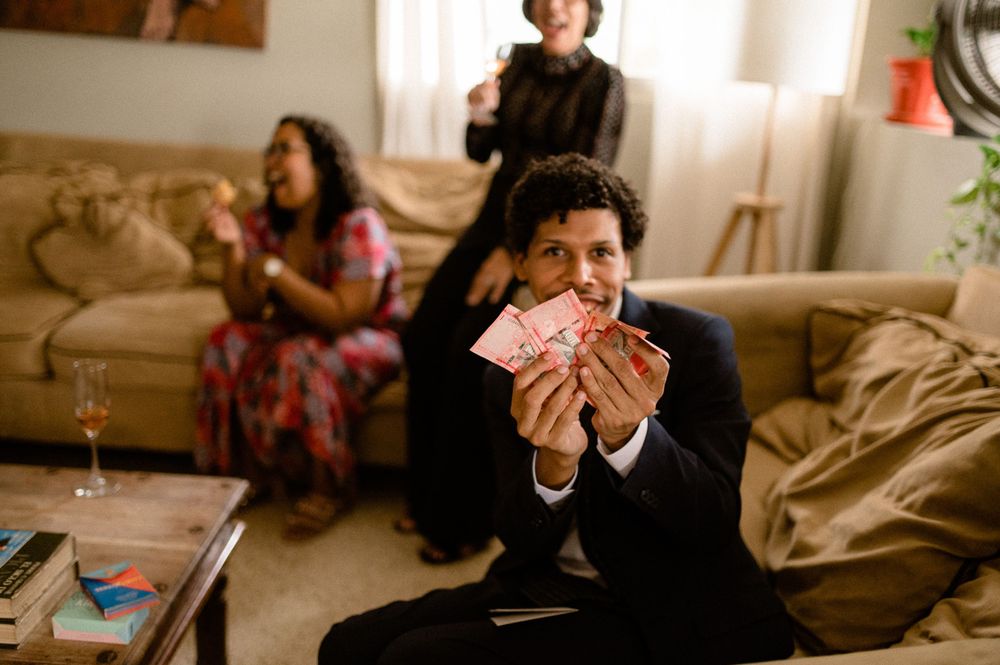 Gathering in living room with person holding cards while others relax on couch.