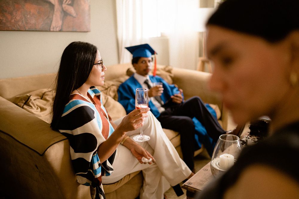 Graduates celebrating and chatting together on a couch in their caps and gowns.