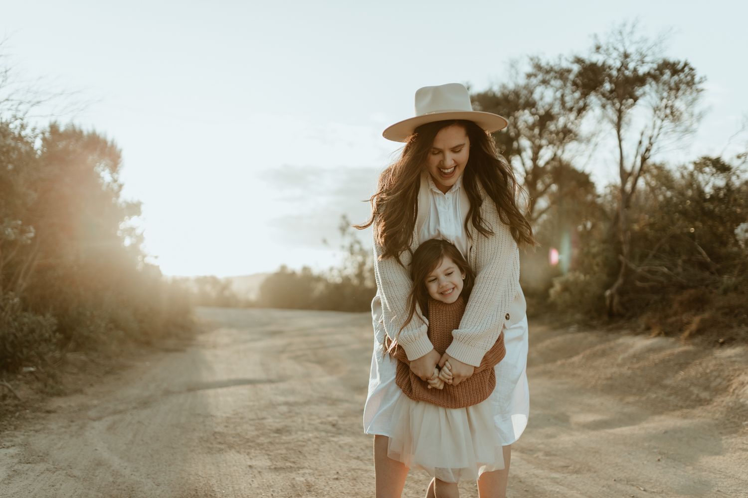 A playful piggyback ride moment captured on a dirt path at sunset.