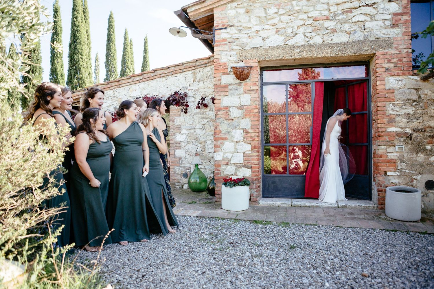 The bride emerges from a door of the Lazy Olive to reveal her wedding dress to her bridesmaids.