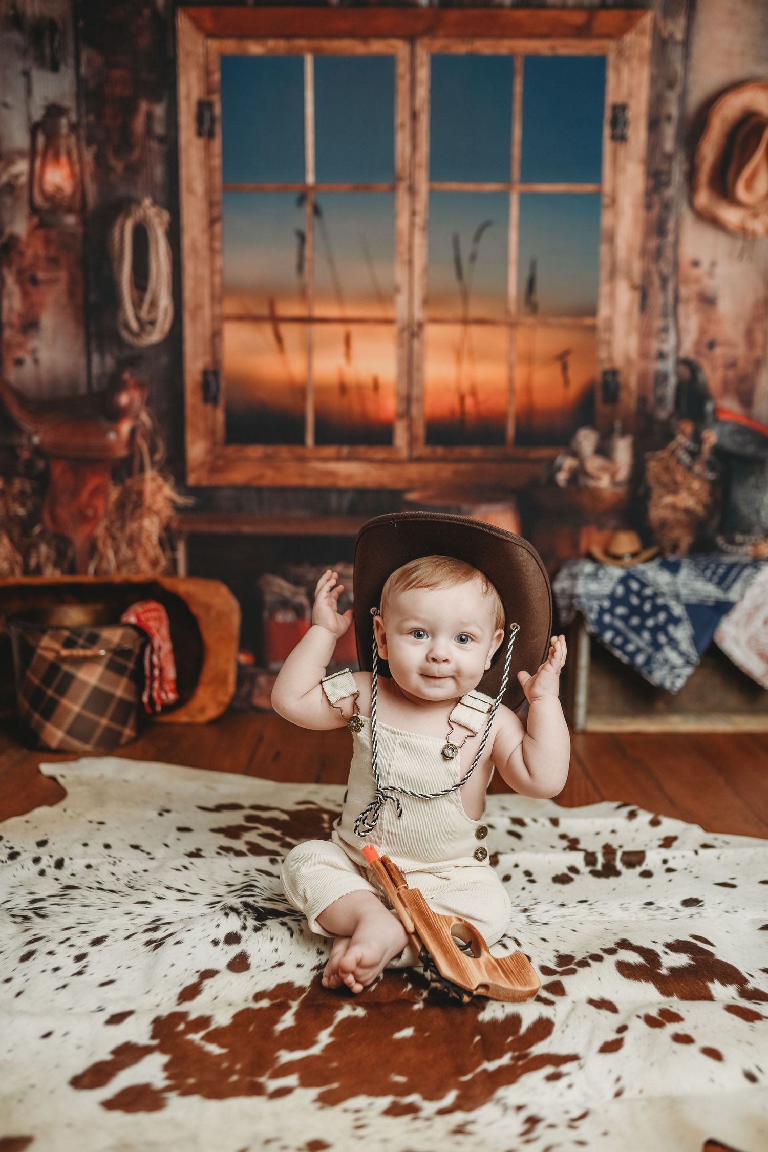 Western-themed photo setup with cowhide blanket and rustic windows in background.