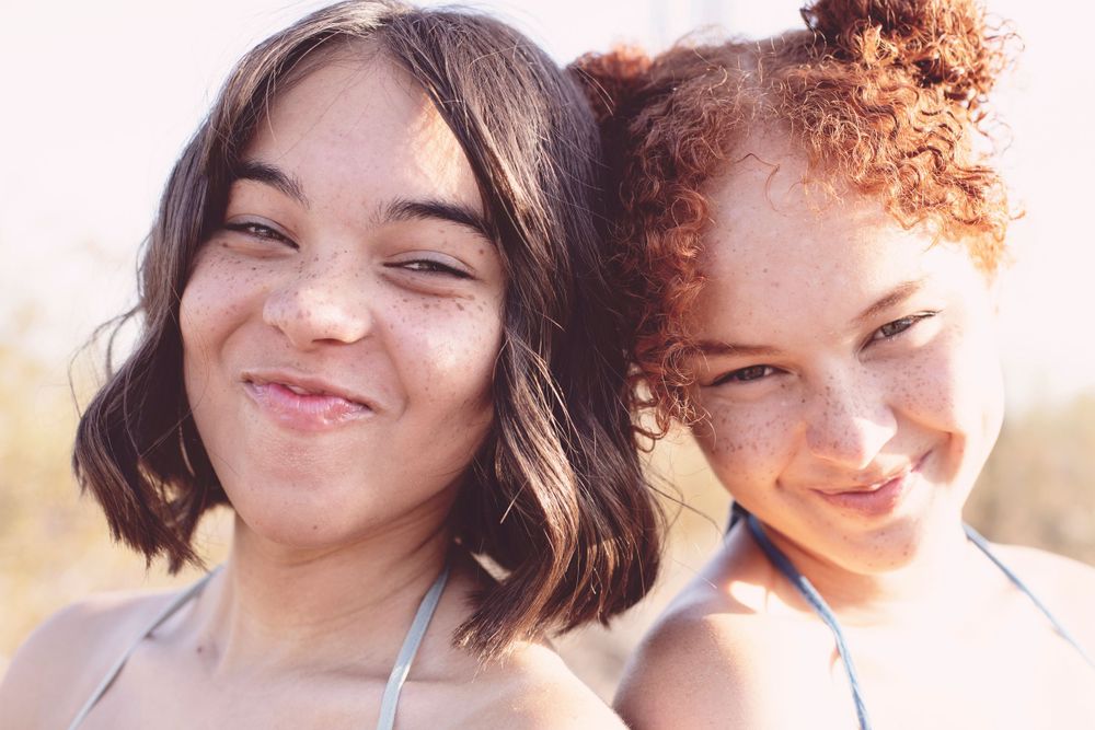 Close-up smiling portrait with warm golden sunlight in desert background.