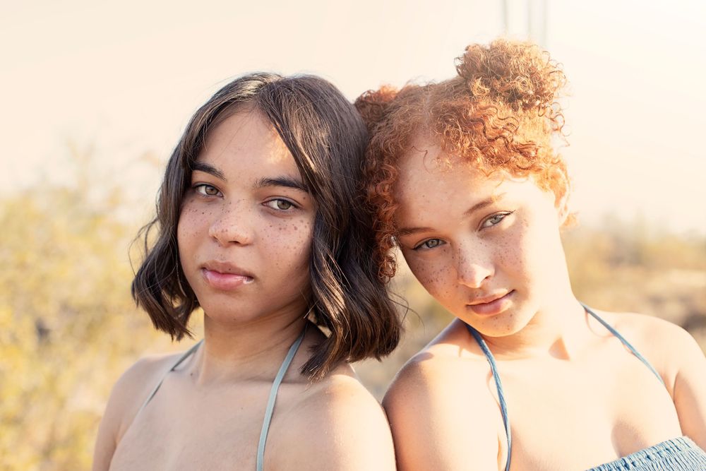Close-up portrait shot of two people with warm sunset lighting in desert setting.