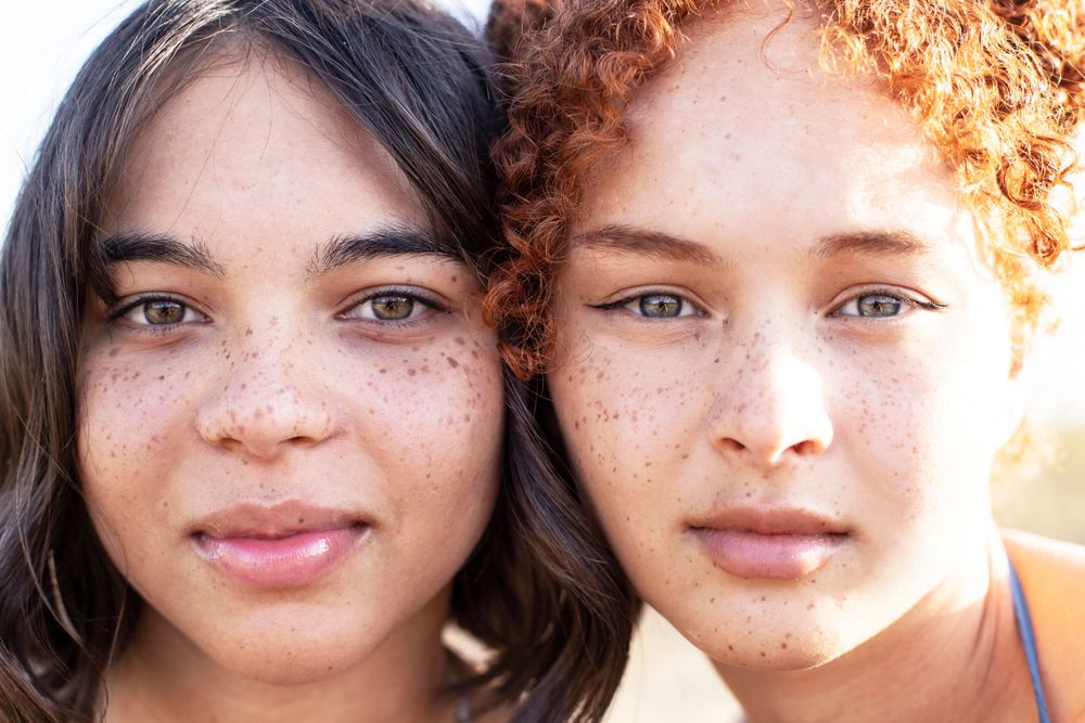 Close-up portrait of two people smiling warmly in desert sunlight.