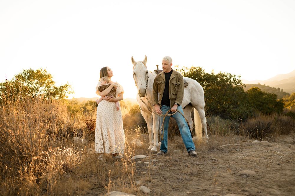 Ojai horse ranch family photos by Ventura family photographer of couple with their baby and horse during sunset in river preserve