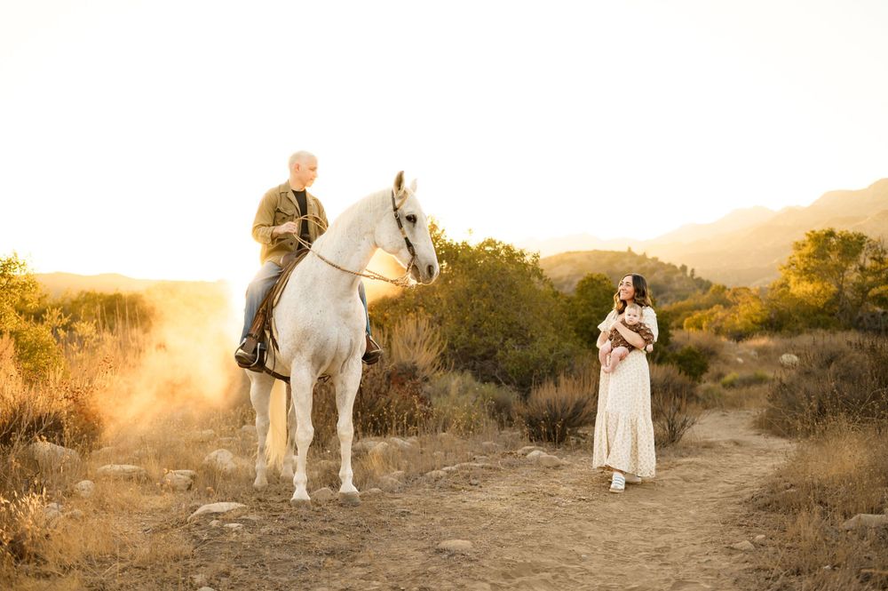 Ojai horse ranch family photos by Ventura family photographer of couple with their baby and horse during sunset in river preserve