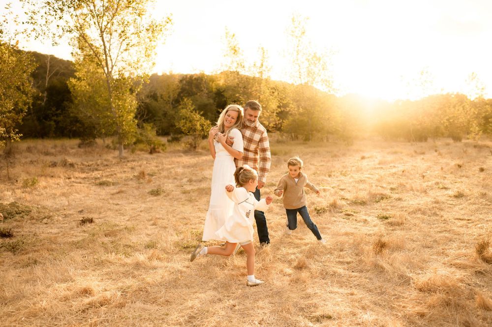 Santa Barbara golden grassy field family photos by Ventura family photographer of family playing chase in sunlight during photoshoot