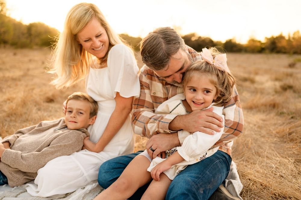 Santa Barbara golden grassy field family photos by Ventura family photographer of family cuddled up on blanket in sunlight during photoshoot