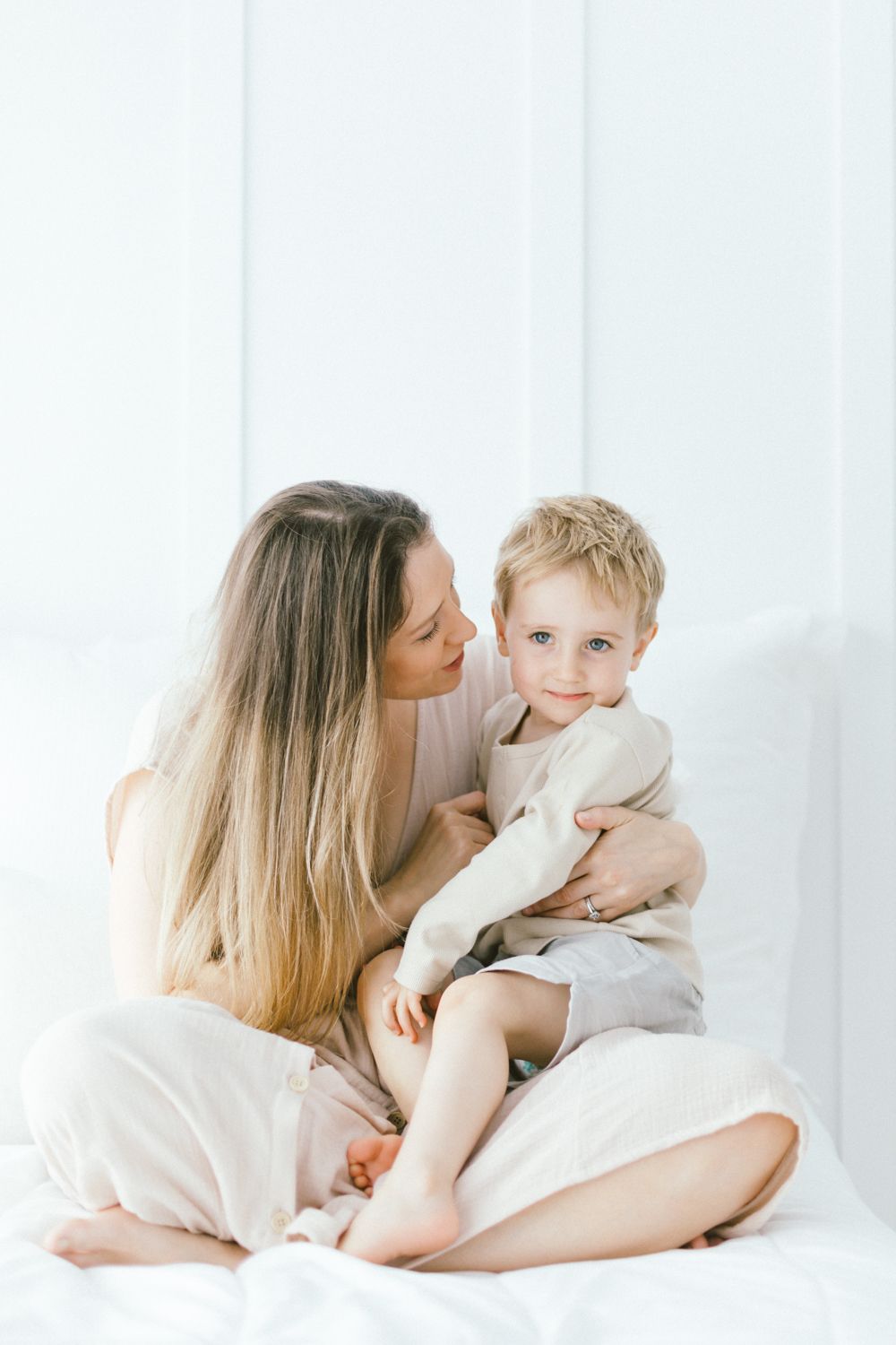Intimate family cuddle session captured in soft, bright lighting.
