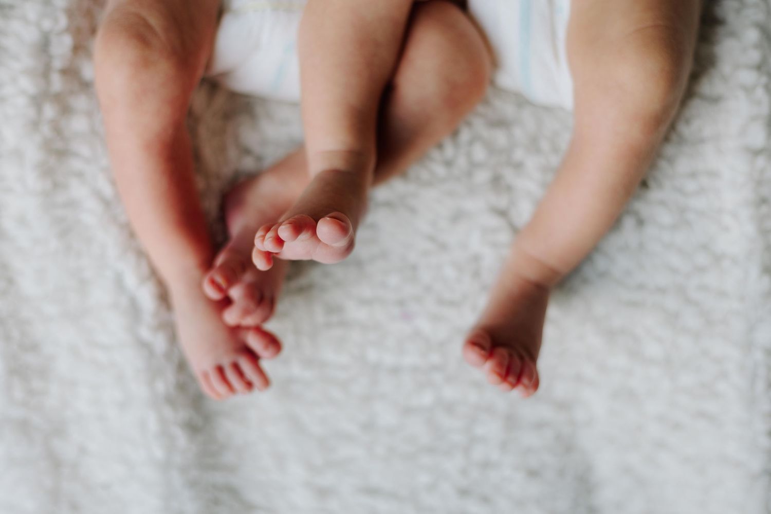 Close-up shot of tiny baby feet against a white textured background.