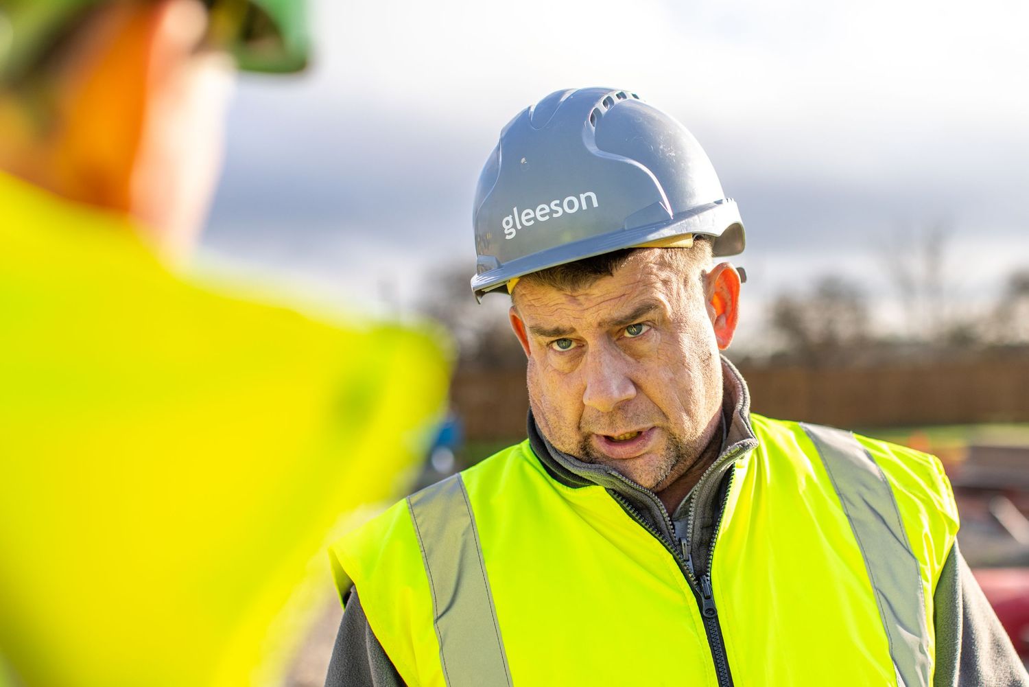Construction worker in protective gear supervising at work site.