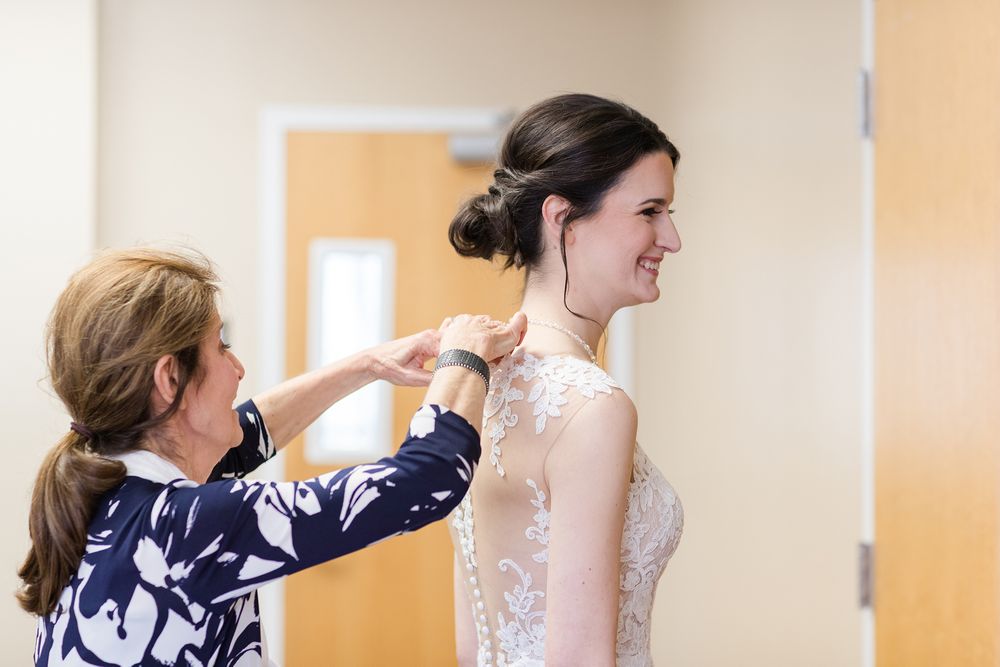 A touching wedding preparation moment with final dress adjustments being made.