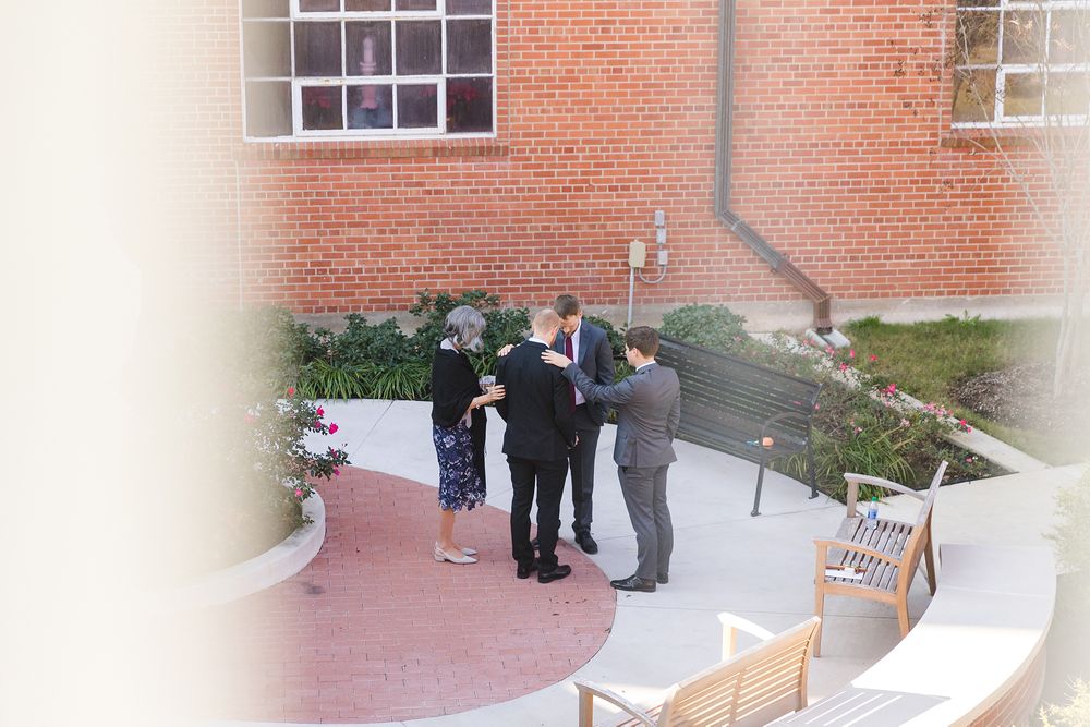 Small wedding ceremony gathering outside brick building entrance.