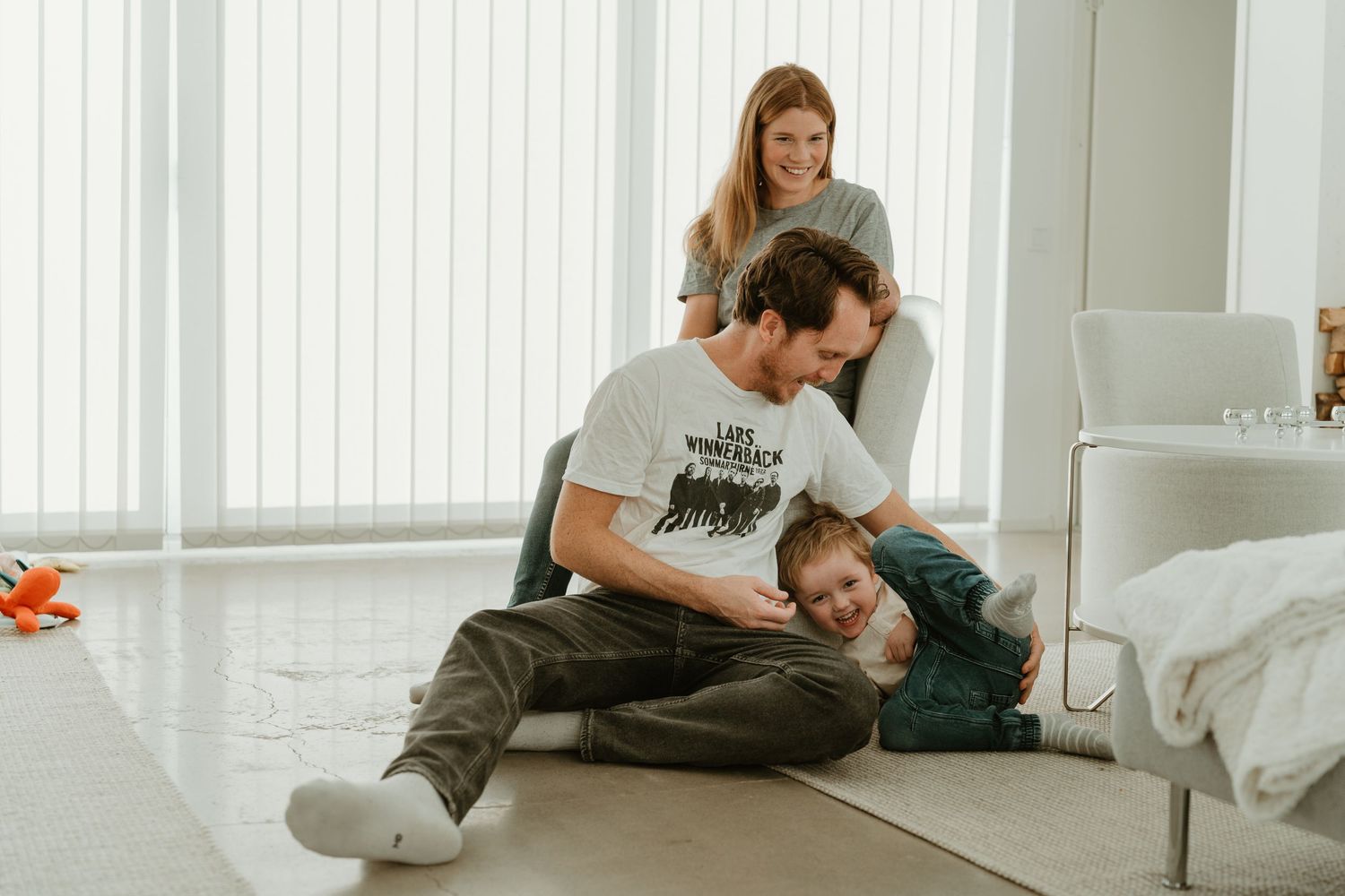 Casual family moment in a bright, modern living room with white decor.