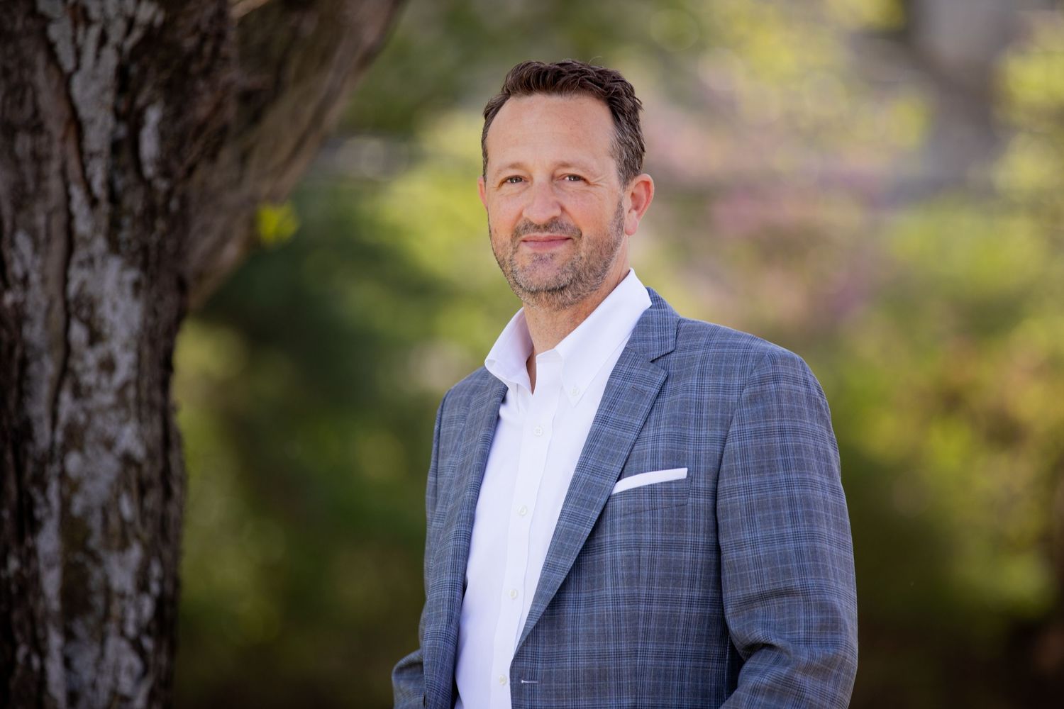 Professional business portrait outdoors with natural blurred background.