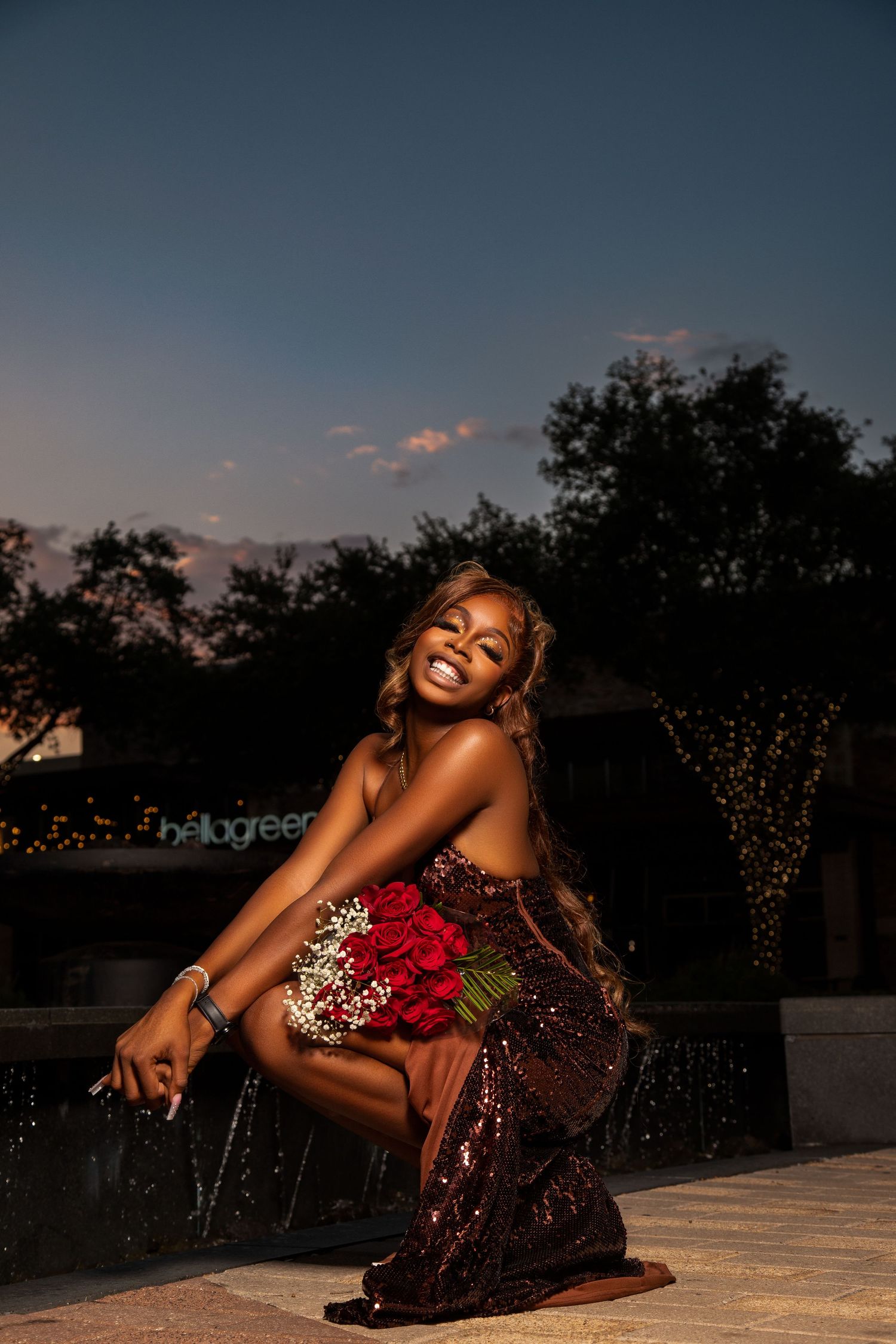 Elegant sunset portrait with sparkly dress and red roses in outdoor setting.