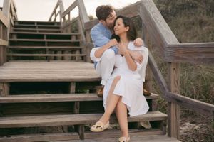 Romantic couple sharing intimate moments on wooden beach bleachers at sunset.