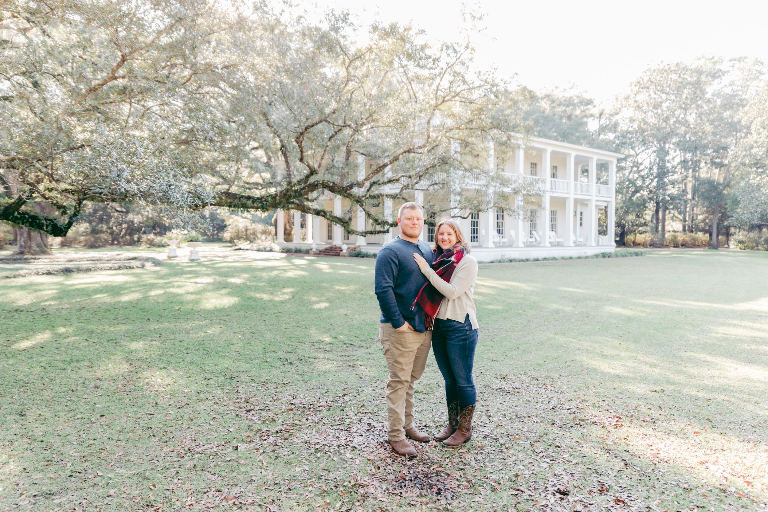 Romantic couple walking together on a scenic path near a white colonial building.