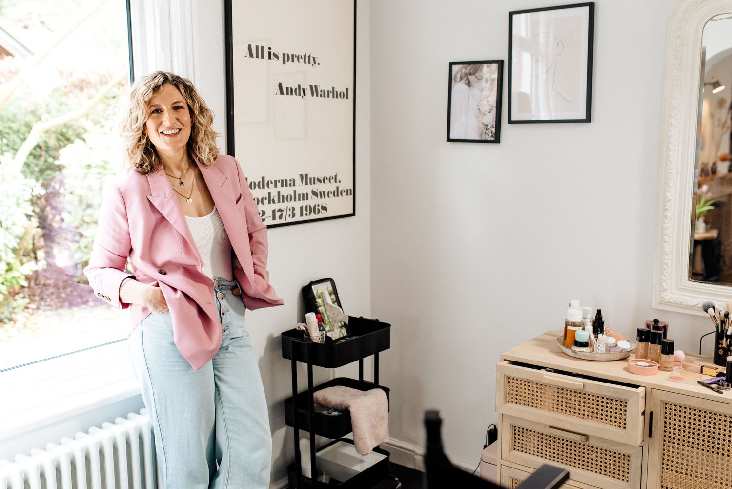 Stylish pink blazer outfit photographed in a modern office space with framed artwork.