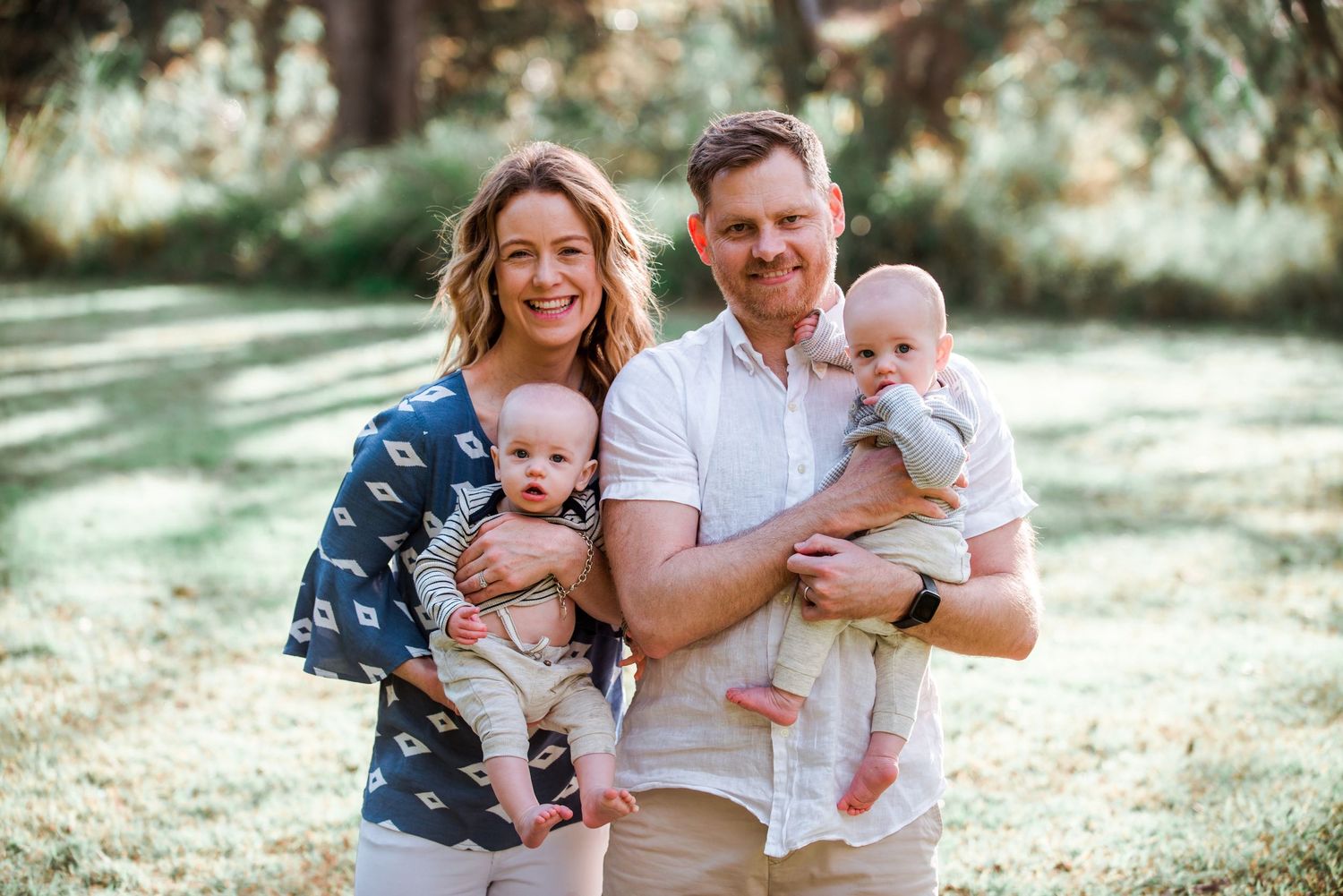 Family portrait outdoors with twins and parents wearing coordinating casual outfits.