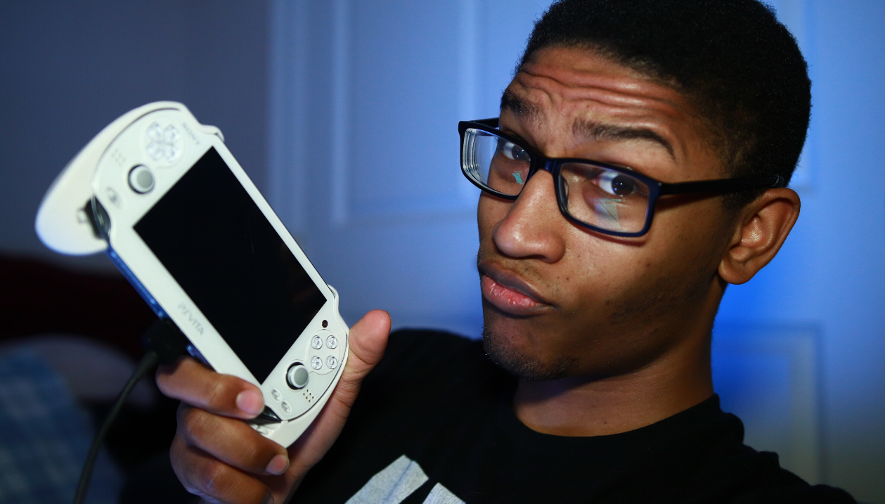Black man holding a white playstation vita, ps vita, with a blue background