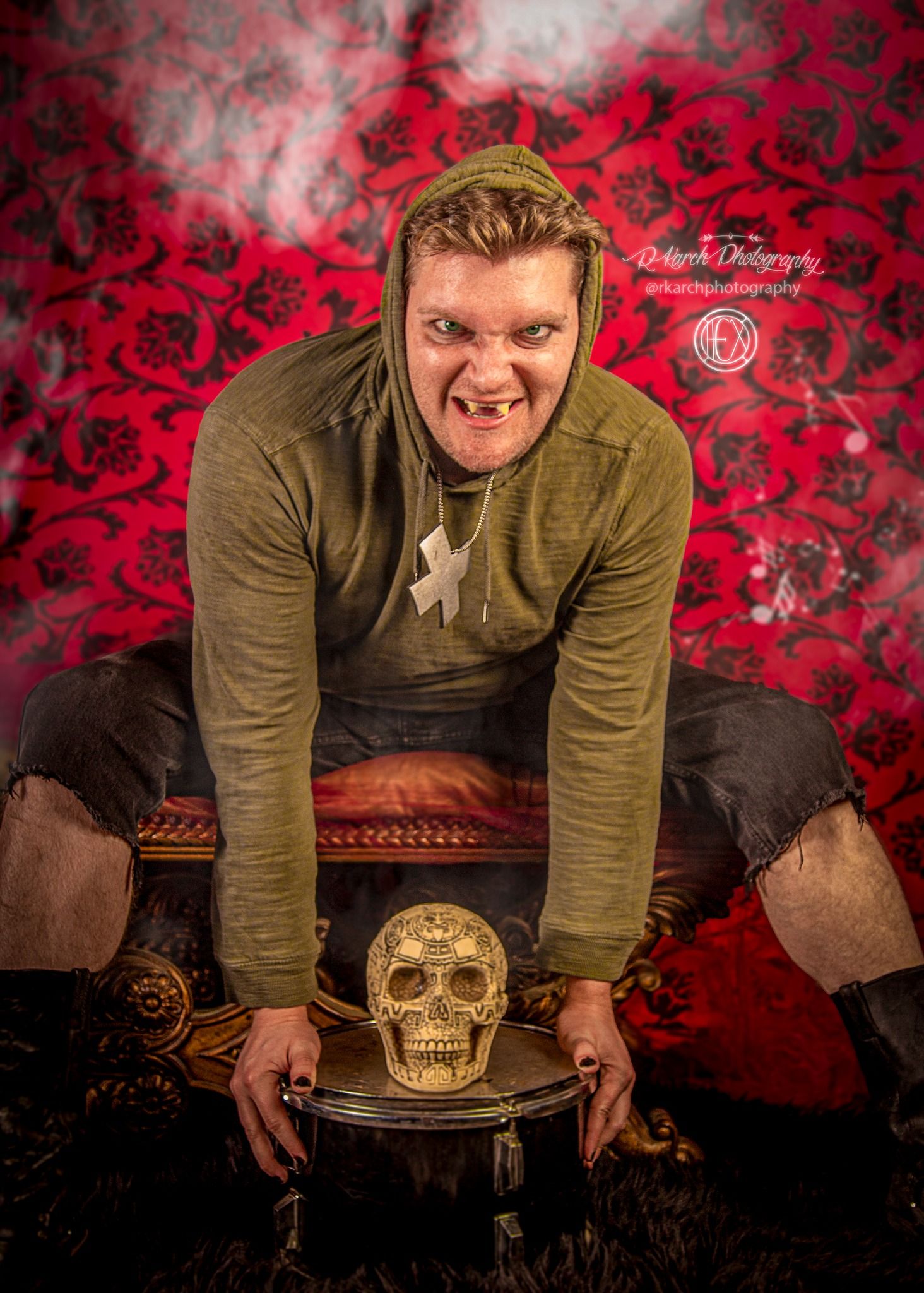 Dramatic portrait with skull prop against red floral backdrop.