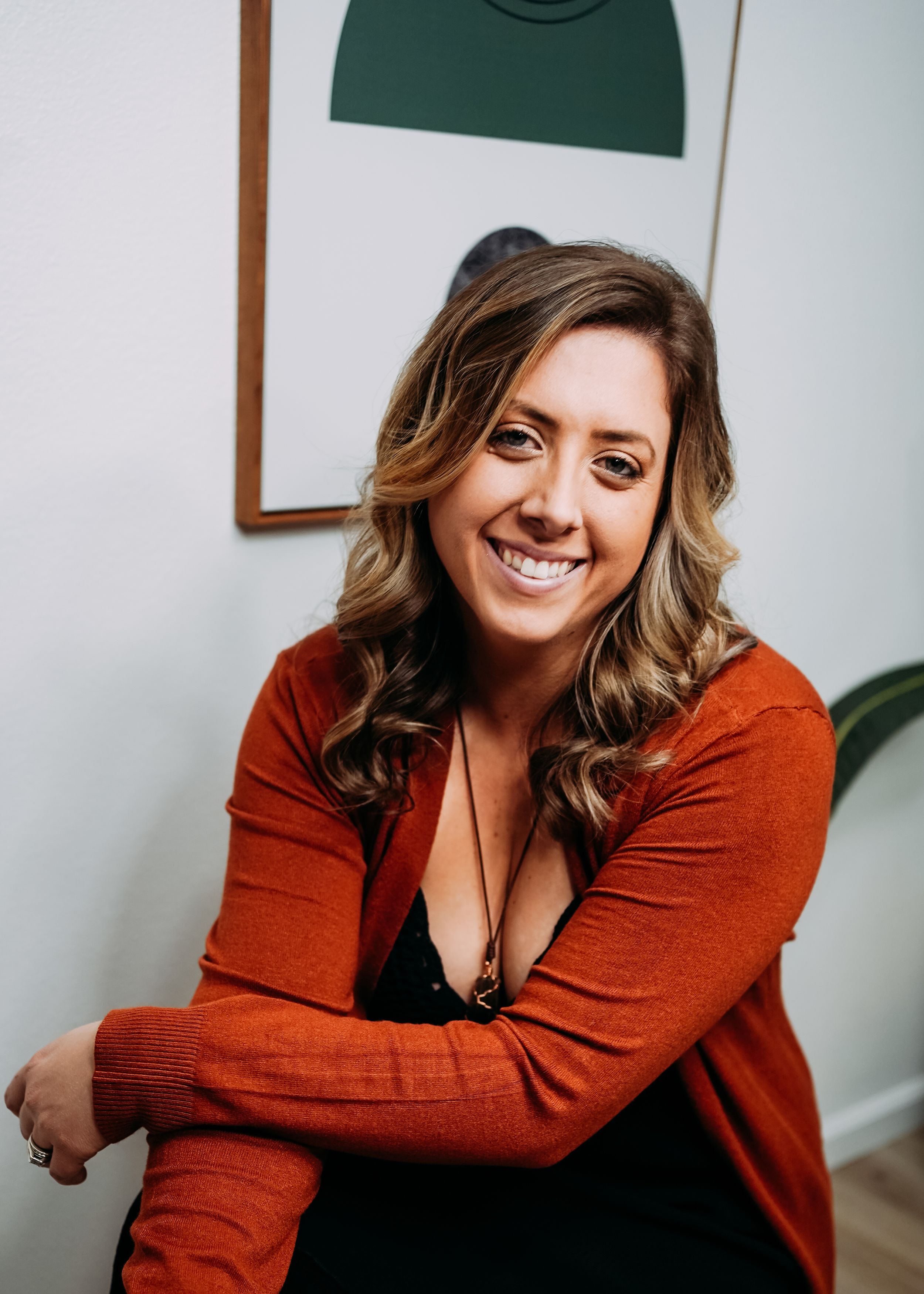 Missy, a smiling woman with wavy hair, wears an orange cardigan and a black top.
