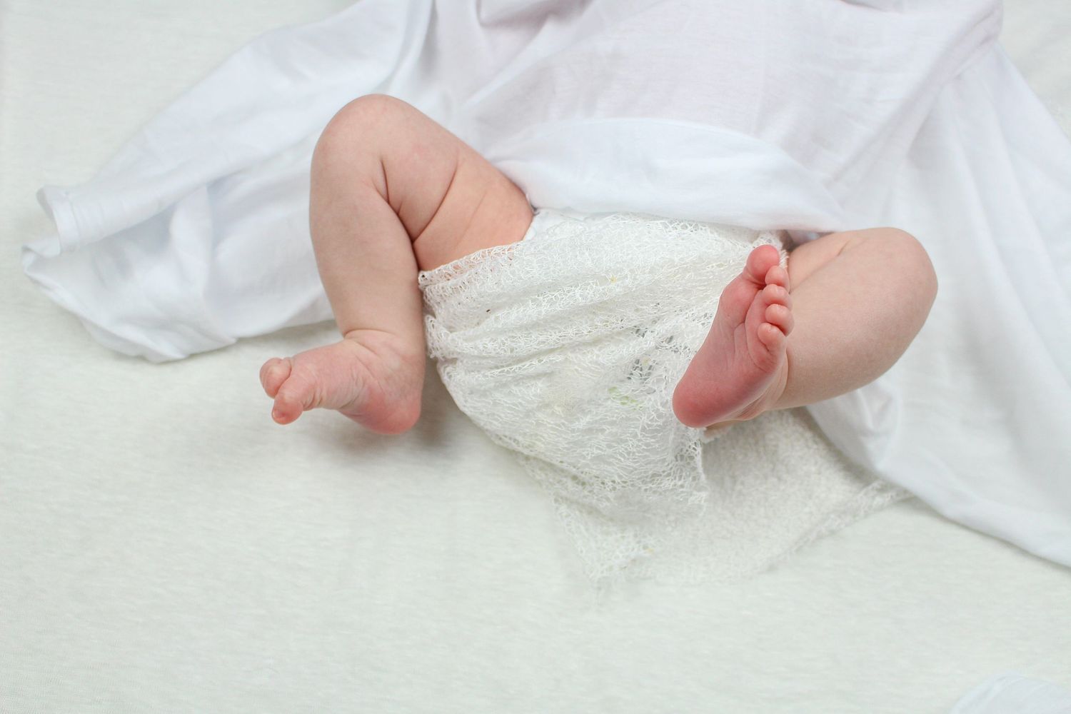 Close-up of tiny baby feet wrapped in soft white blankets.