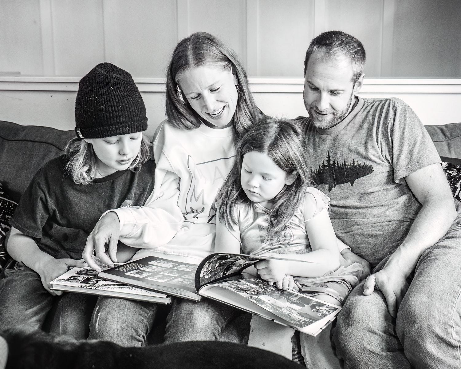 Black and white image of people reading together on a couch.