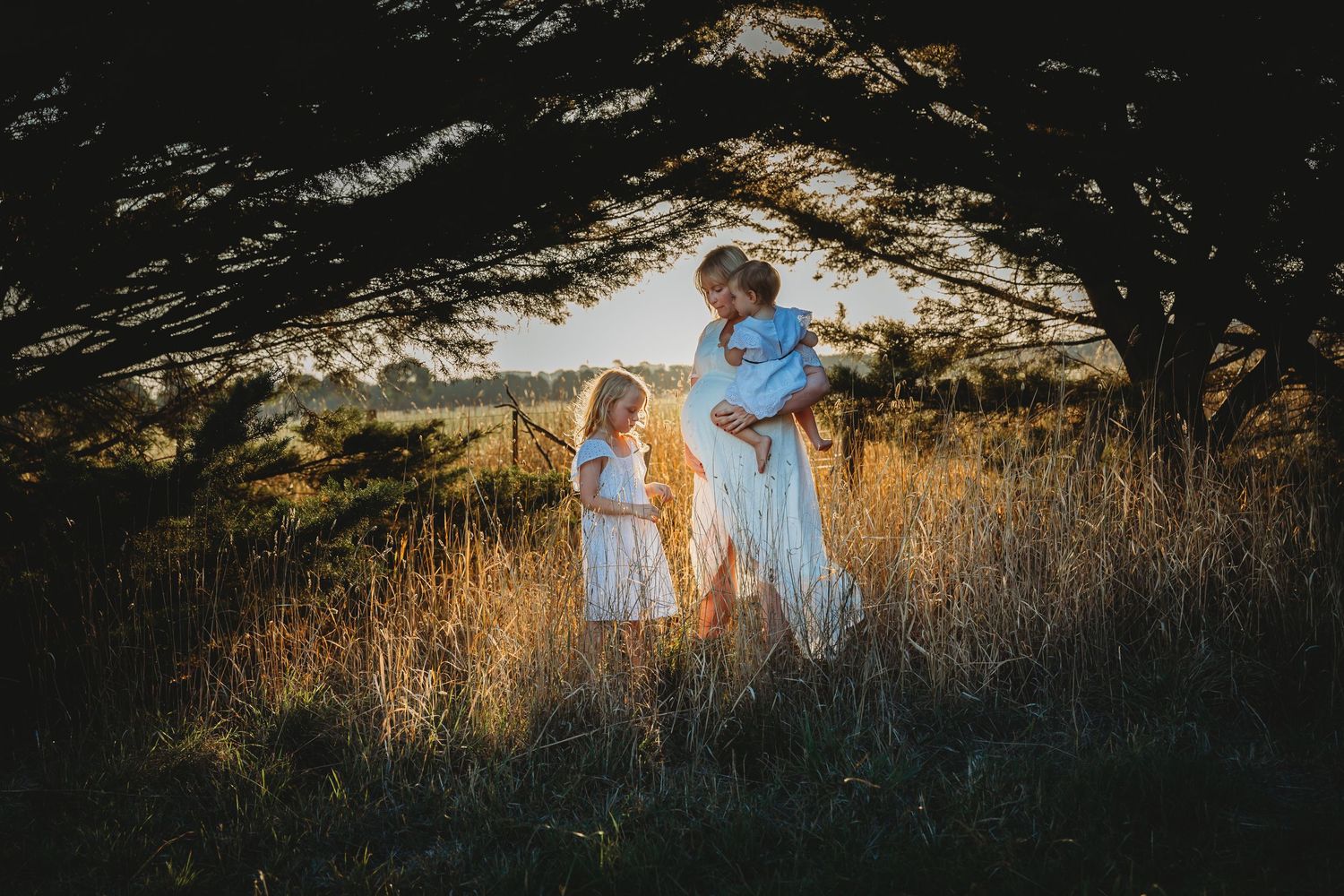 Motherhood, a pregnant woman dressed in white with her daughters