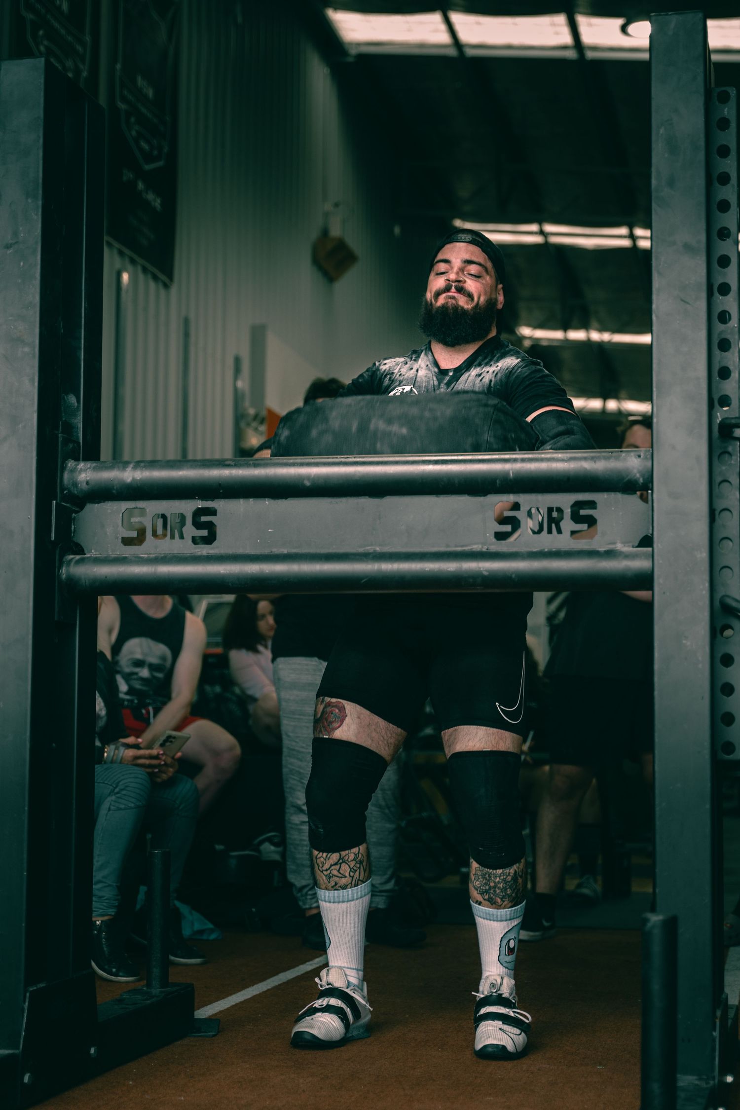 Athlete preparing for lift inside power rack at strength training facility.