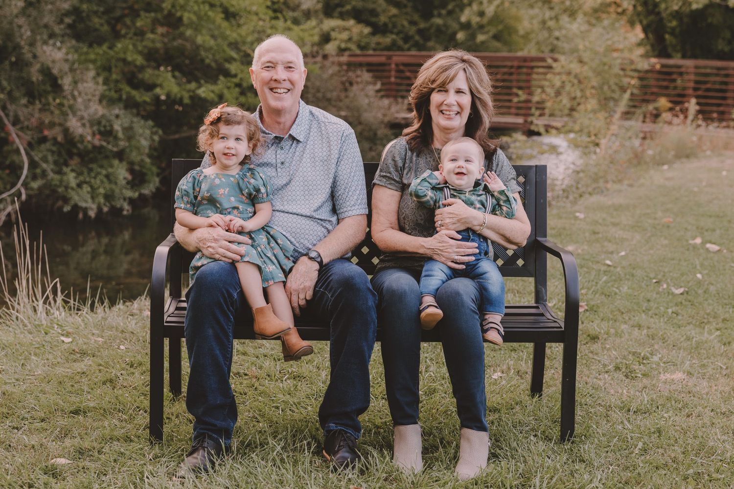 Two generations share a moment together while seated on an outdoor bench in a natural setting.