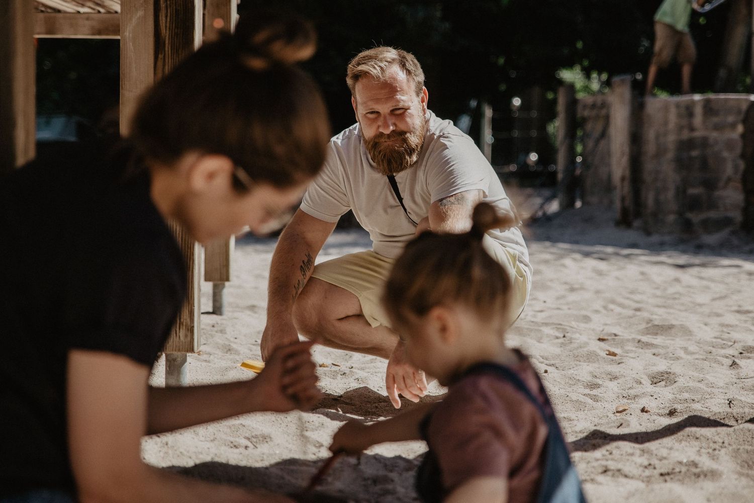Eine Gruppe spielt an einem sonnigen Tag gemeinsam im Sand auf einem Spielplatz.