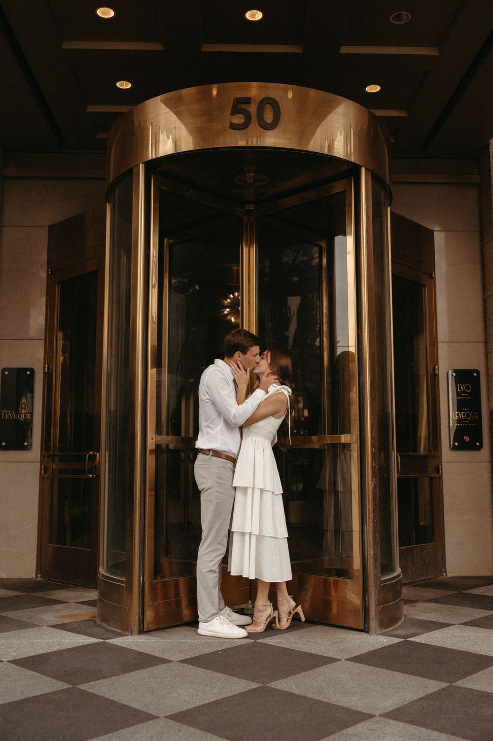 A romantic moment shared in an elegant revolving doorway entrance.