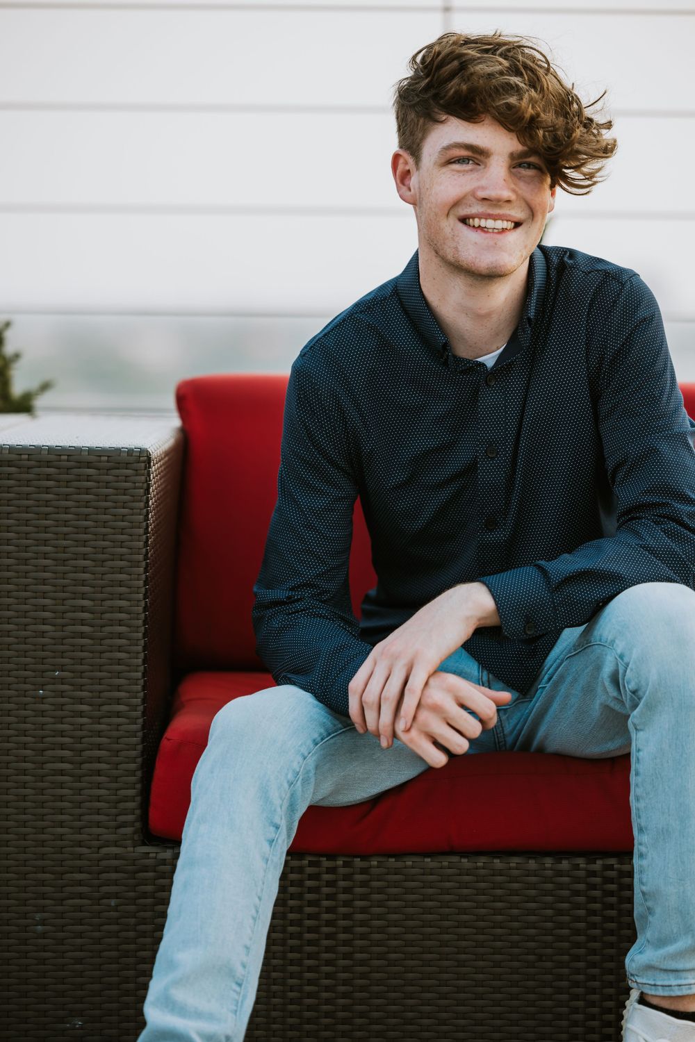 Casual portrait on outdoor patio furniture with red cushions.