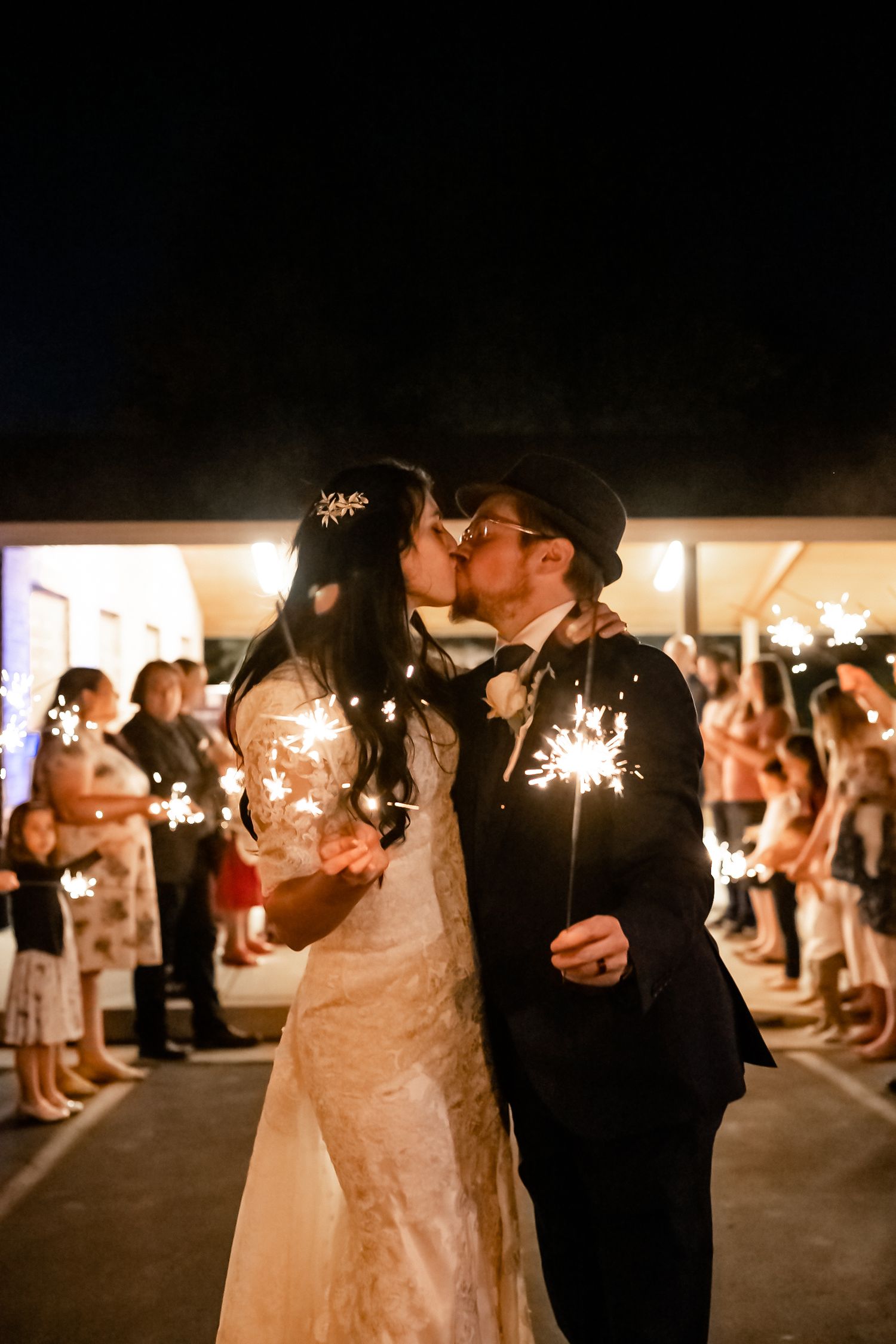 Wedding guests hold sparklers during a nighttime celebration send-off.