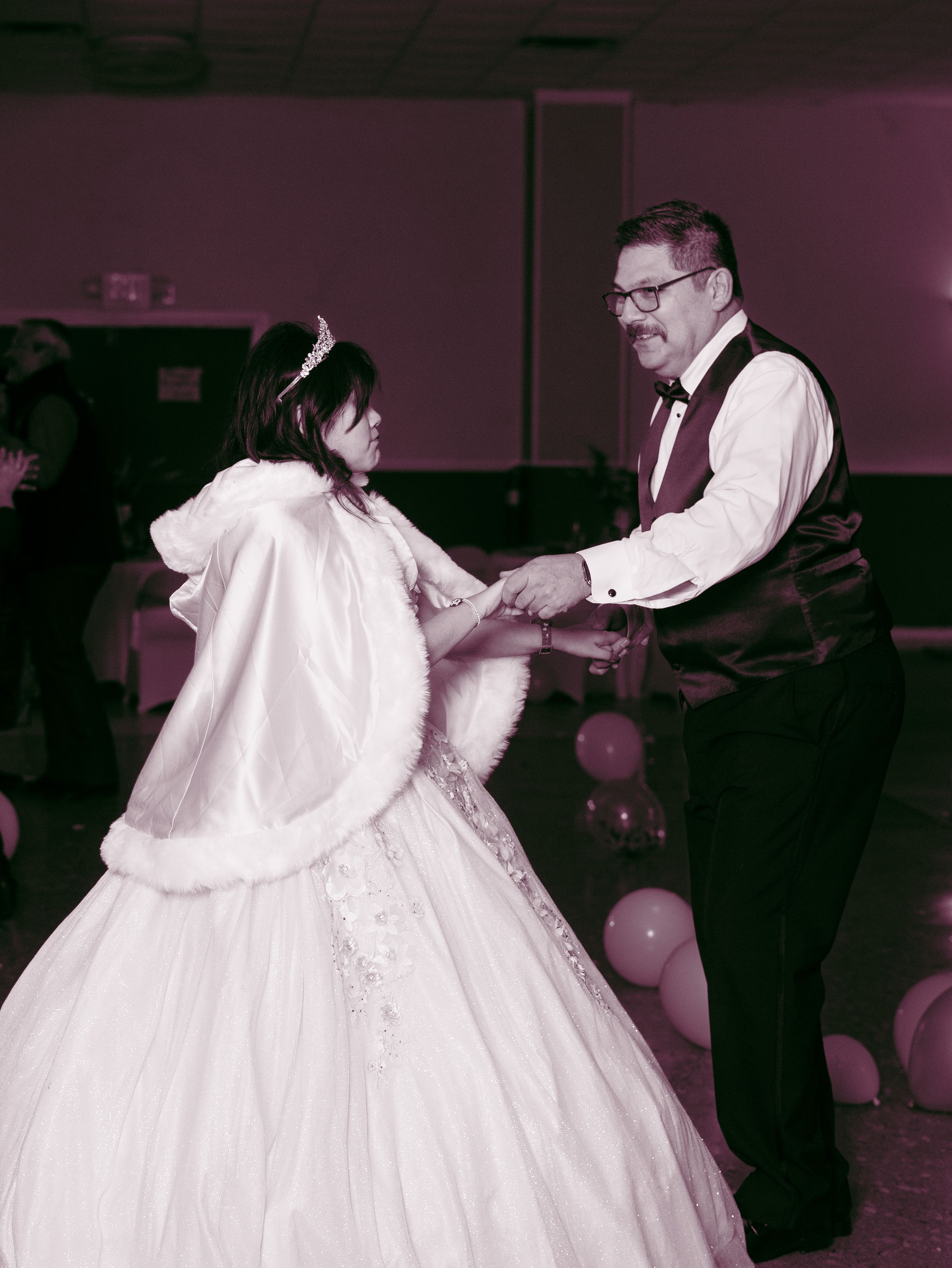 A couple dancing at a celebration event with the person wearing an elegant white ballgown with fur trim.