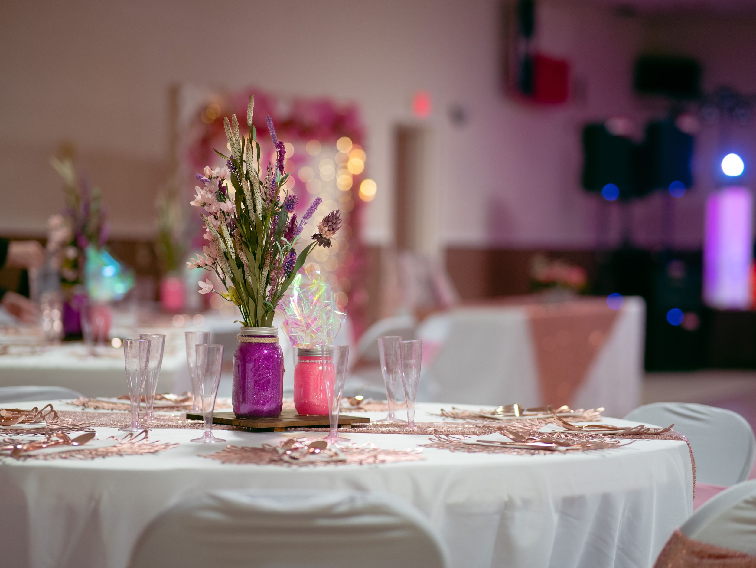 Elegant wedding table setting with pink floral centerpiece and rose gold accents.