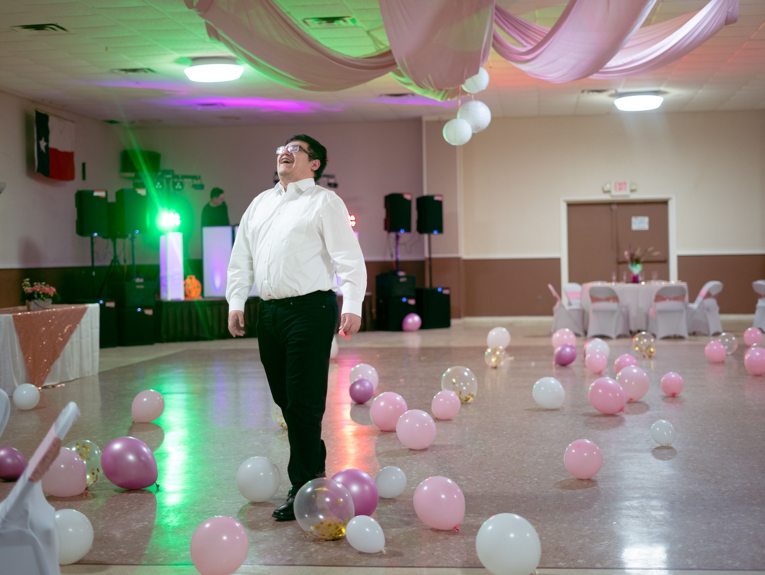 Reception hall decorated with pink and white balloons and colorful lighting effects.