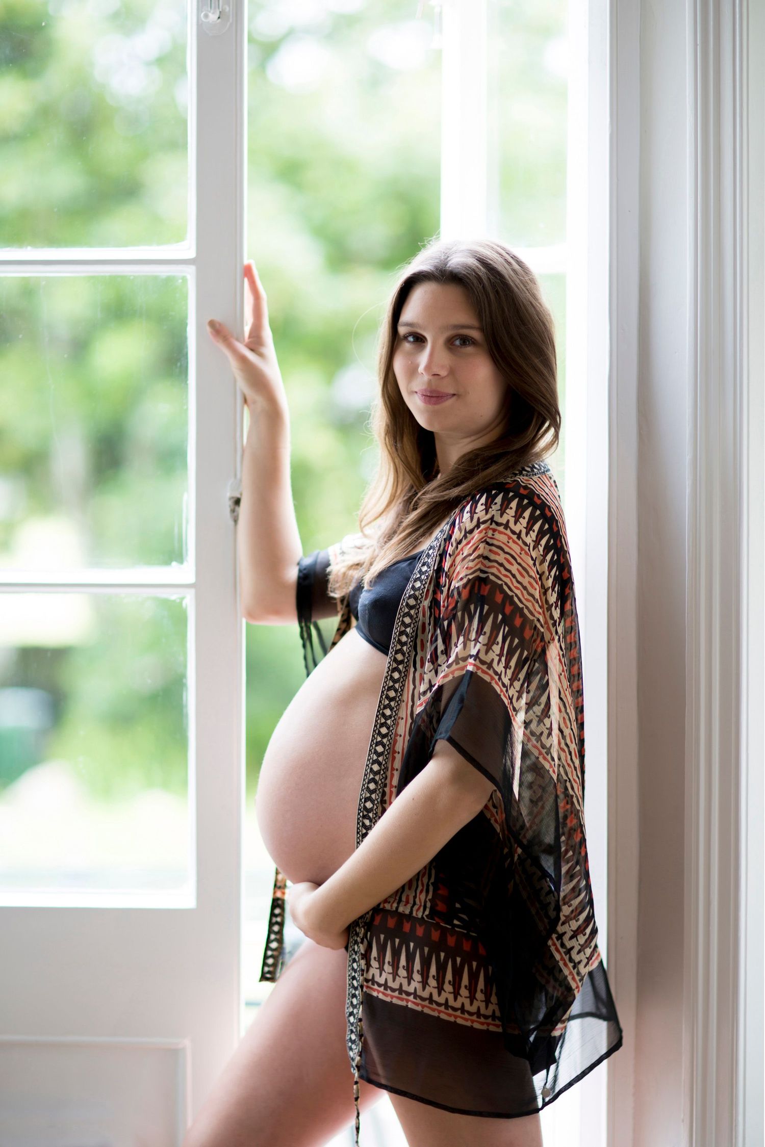 Maternity portrait by window showing pregnant silhouette in patterned kimono.
